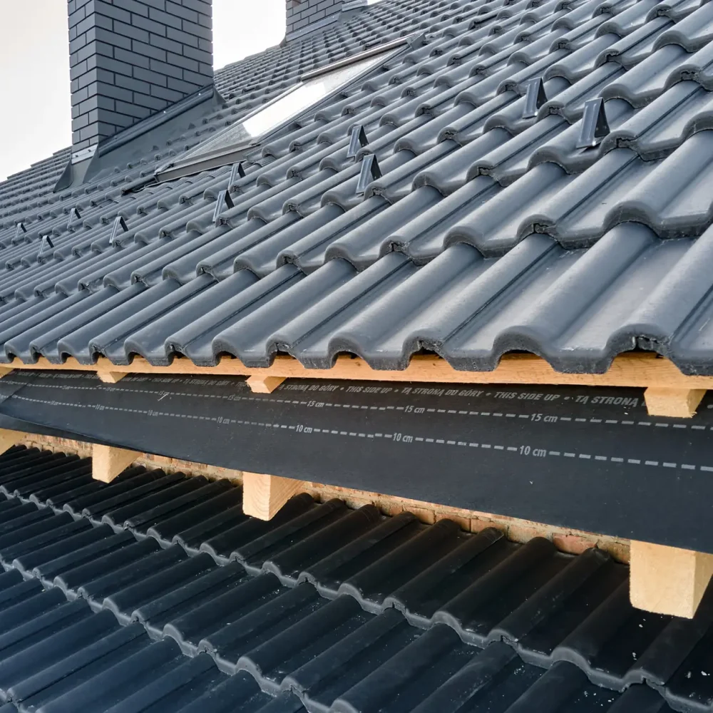 Closeup of house roof top covered with ceramic shingles. Tiled covering of building under construction.