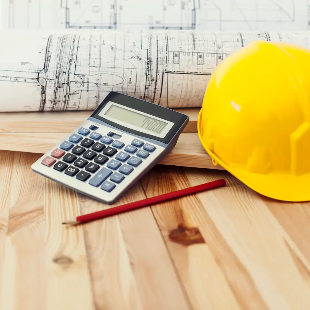 Yellow helmet with blueprints and calculator on wood
