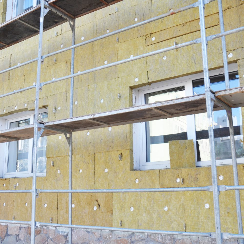 Install Rock Mineral Wool Insulation. Energy efficiency house wall renovation for energy saving. Exterior house wall heat insulation with mineral wool, building under construction.